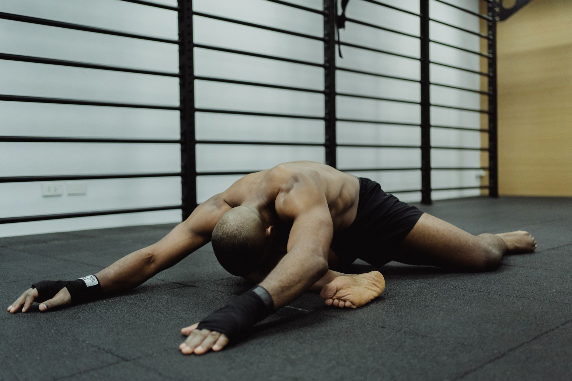 bald man sitting on a floor with black mat